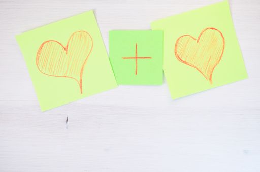An overhead shot of two illustrated hearts and a plus sign in between on white background - marriage, union concept