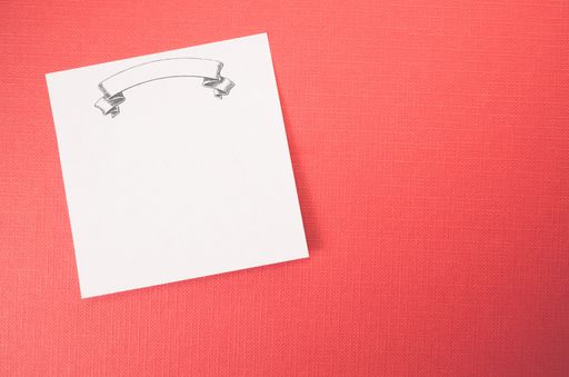A white blank memo with blank banner on a red textured surface - abstract backgrounds with space for your text