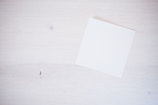 A white blank memo on a white textured surface - abstract backgrounds with space for your text