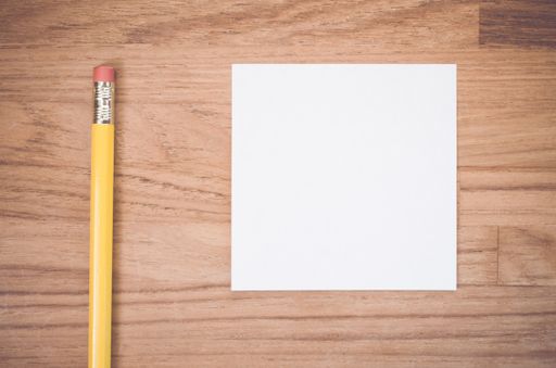 A flat lay of a white blank memo and pencil  on a wood textured surface with space for your text