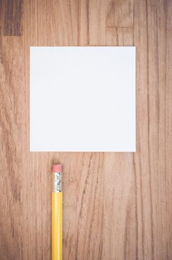 A vertical shot of a white blank memo and pencil  on a wood textured surface with space for your text