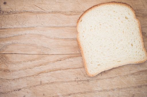 A flat lay of a slice of white bread on a wooden table with space for your text