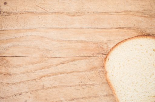 A flat lay of a slice of white bread on a wooden table with space for your text