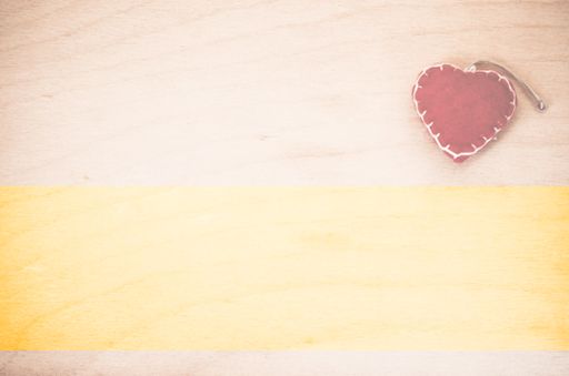 An overhead shot of hand made red felt heart decoration on a natural wood background