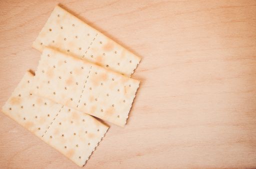 An overhead shot of crispy crackers on a wood textured surface with space for your text