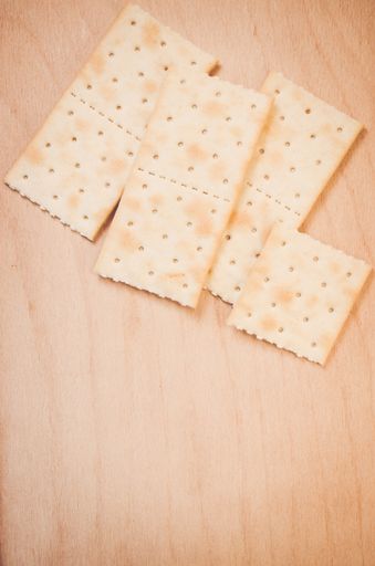A vertical shot of crispy crackers on a wood textured surface with space for your text