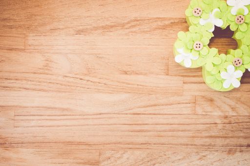 An overhead shot of handmade green Easter flower decoration on a wooden surface with space for your text