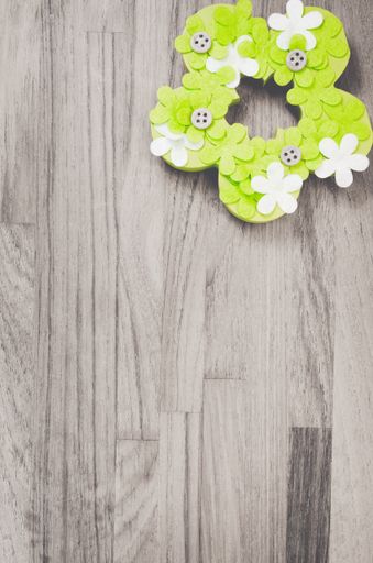 A color burst of green handmade Easter flower decoration on a grayscale wooden surface with space for your text