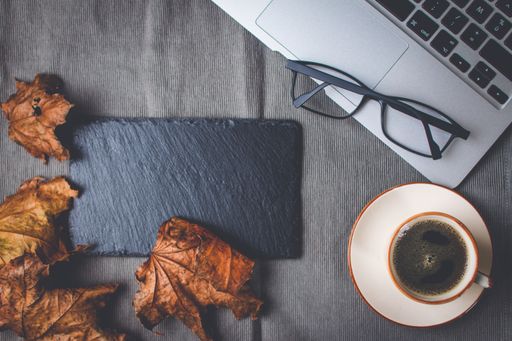 A top view of a working table with a cup of coffee and a notepad