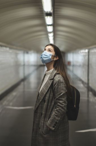 A vertical shot of Caucasian woman wearing a face mask in a subway tunnel - new normal concept
