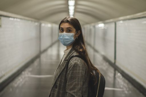 A young Caucasian woman wearing a face mask in a subway tunnel - new normal concept