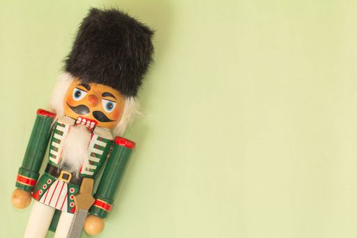 Interesting beautiful christmas nutcracker soldier on green colored paper surface texture with copy space.