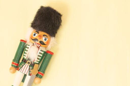 Interesting beautiful christmas nutcracker soldier on yellow colored paper surface texture with copy space.