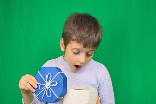 A closeup shot of a cute boy holding a present and posing for the camera