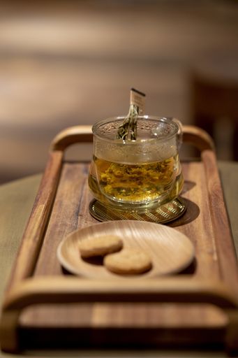 A vertical shot of a jar of honey and fresh cookies on a wooden tray