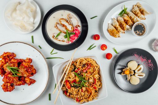 A top view closeup of the plates of Chinese foods on a white table