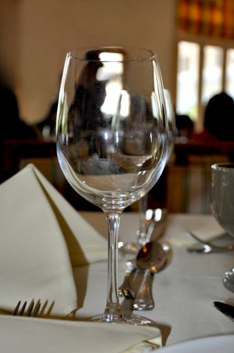 A vertical closeup shot of a clean empty wineglass on a restaurant table