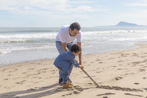 A cheerful father and son playing on the sandy seashore
