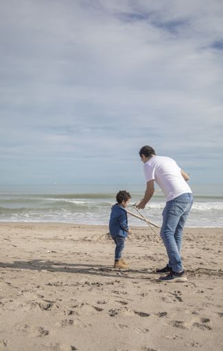 A cheerful father and son playing on the sandy seashore