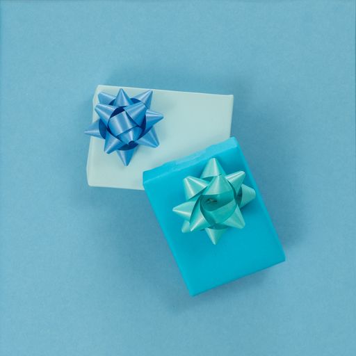 A top view isolated shot of gift boxes wrapped in light blue and turquoise blue paper with ribbons on a light blue background