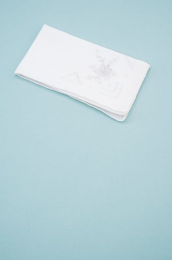 A white handkerchief with a flower on it on a light blue background