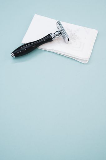 A silver shaving razor with black handle on a white handkerchief