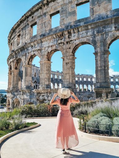 A vertical shot of a lady in front of the Coliseum in Rome, Italy