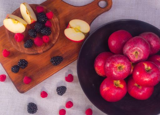 A high angle shot of ripe red apples with raspberries and blackberries on the table