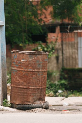 A vertical shot of a rusty, dented, old metal barrel on an old motorbike tire