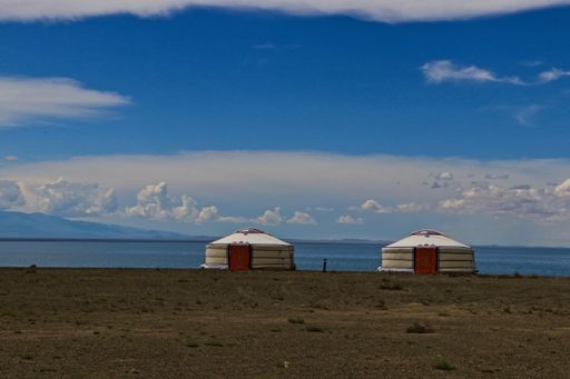 A beautiful shot of traditional yurts with mountains in the background under the cloudy sky