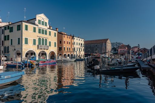 The main canal of the city of Chioggia called Little Venice with its boats reflecting the adjacent buildings and shops on the surface