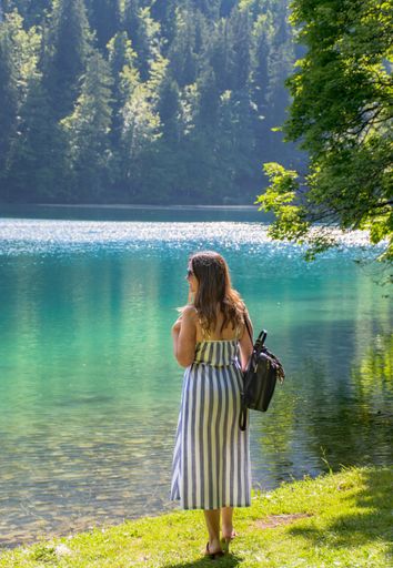 A vertical selective focus shot of a beautiful young lady near a lake on a sunny day