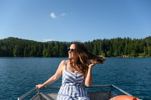 A selective focus shot of a beautiful young lady near a lake on a sunny day