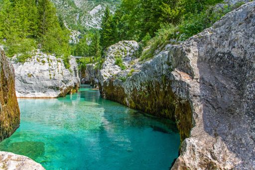 A beautiful view of a lake surrounded by rocky mountains and greenery in Italy
