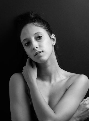 A vertical grayscale shot of a beautiful young lady posing topless