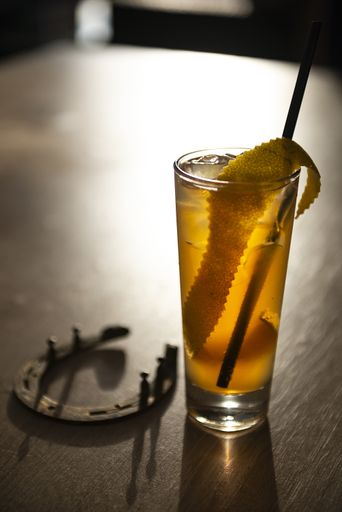 A vertical shot of a cocktail called "Horse's Neck" on a wooden surface