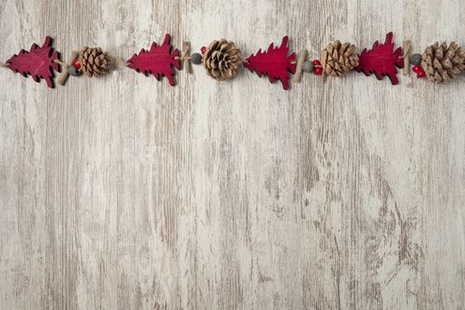A flat lay of colorful Christmas decorations on a bright grained wooden table with a copy space