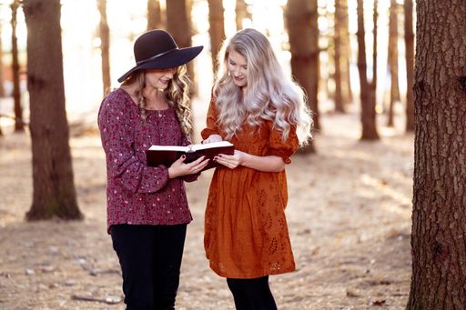 A shot of two young females posing with a book in the forest, autumn mood