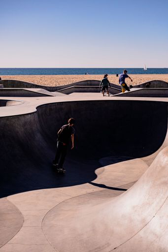 A vertical shot of young males skating at an open-air skatepark near a sea