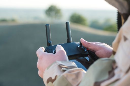 A man holds a remote control while a drone flies