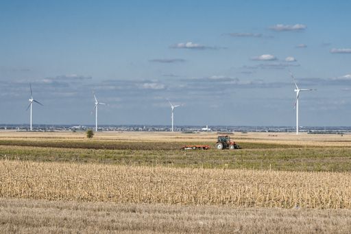 A view of a tractor on a dried field under the blue cloudy sky