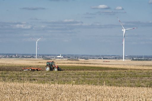 A view of a tractor on a dried field under the blue cloudy sky