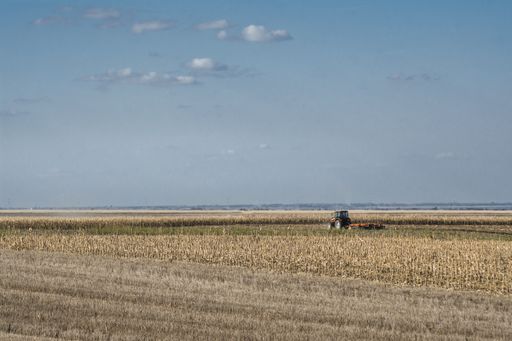 A closeup shot of a tractor working in the field under a blue sky