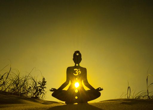 A silhouette of a person meditating with open chakra channels under the sunlight