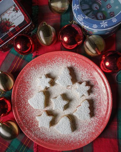 A top view of Christmas tree, bell and star cookies covered with powdered sugar