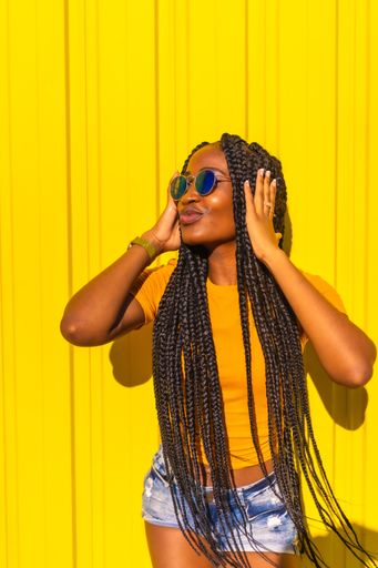 A vertical shot of an African American model posing by a yellow wall