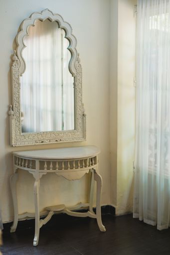 An elaborately shaped vintage mirror with detailed carvings on its white frame in an antique room