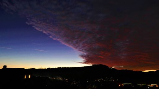 An amazing shot of an illuminated town in a mountain landscape during a deep sunset