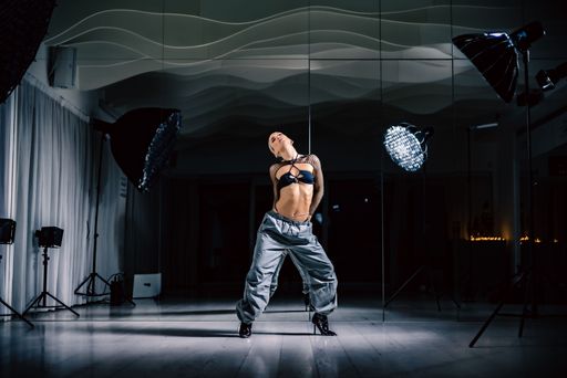 A sexy blonde with long braid ponytail posing in studio with mirrors on the walls in stylish outfit