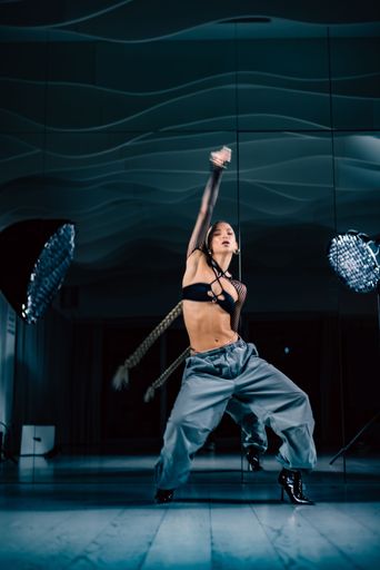 A vertical shot of a beautiful female dancer posing in mesh overlay crop top in black and baggy pants